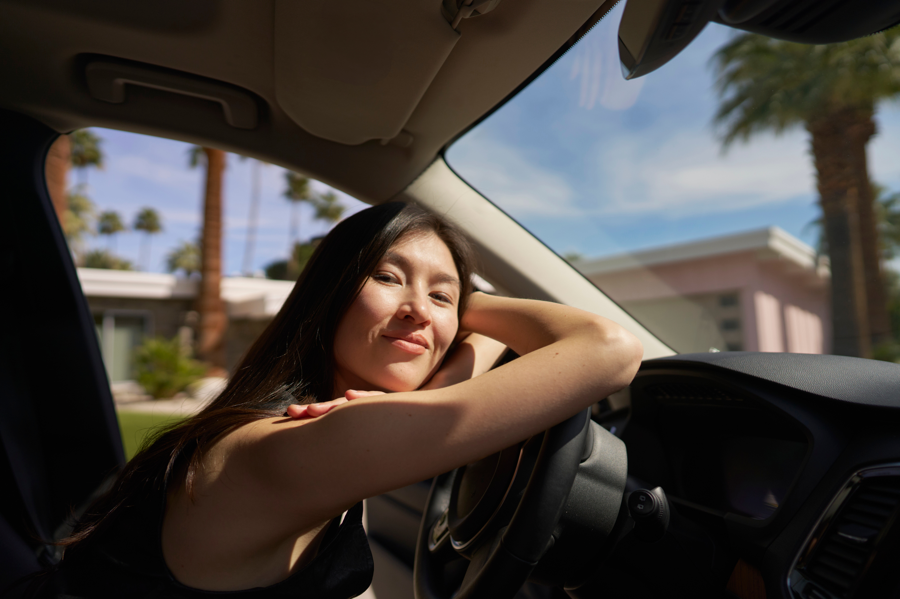 Woman relaxing in a parked car on a sunny day